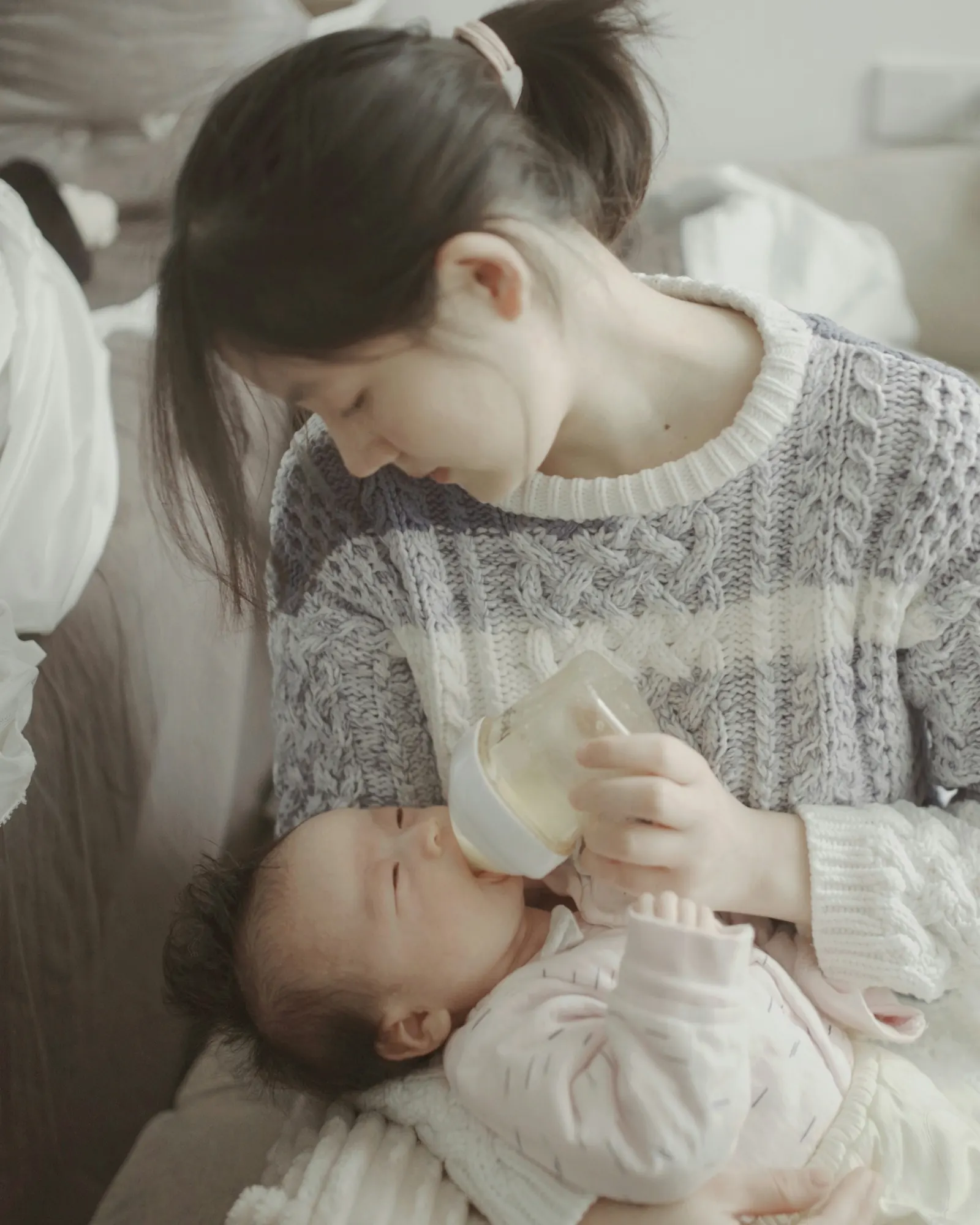 母親抱著新生兒,用奶瓶餵奶